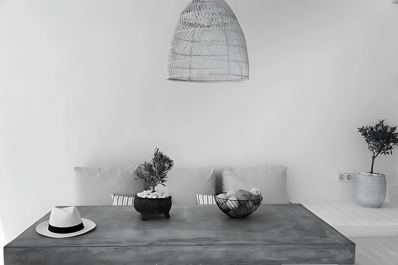 The interior of Calma Suite: cement table, olive tree and rattan light, Milos